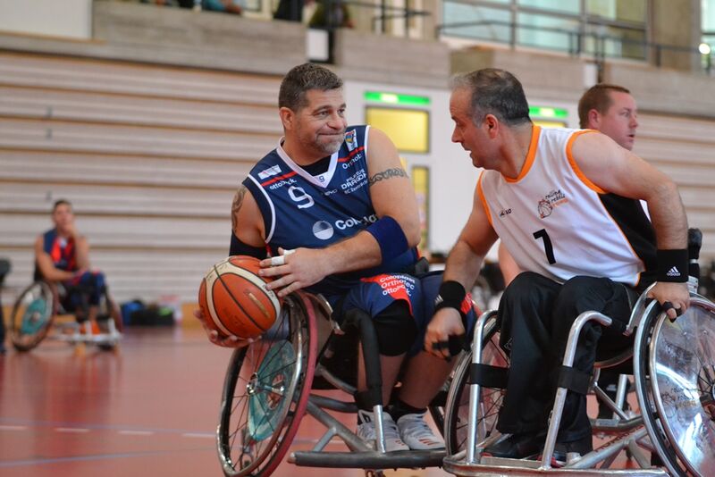 Mark Rothacher verteidigt den Ball gegen einen anderen Spieler, der ihn unten mit dem Rollstuhl berührt.